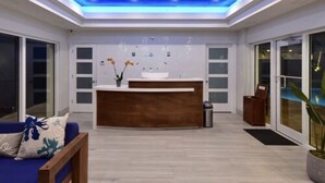 Un área de recepción moderna con un mostrador de madera, un sofá azul y un ventanal grande.