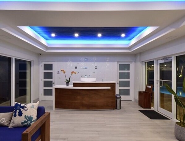 A modern reception area with a wooden reception desk, a blue sofa, and a large window.