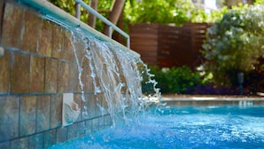 Una piscina con agua cayendo sobre un borde con azulejos.