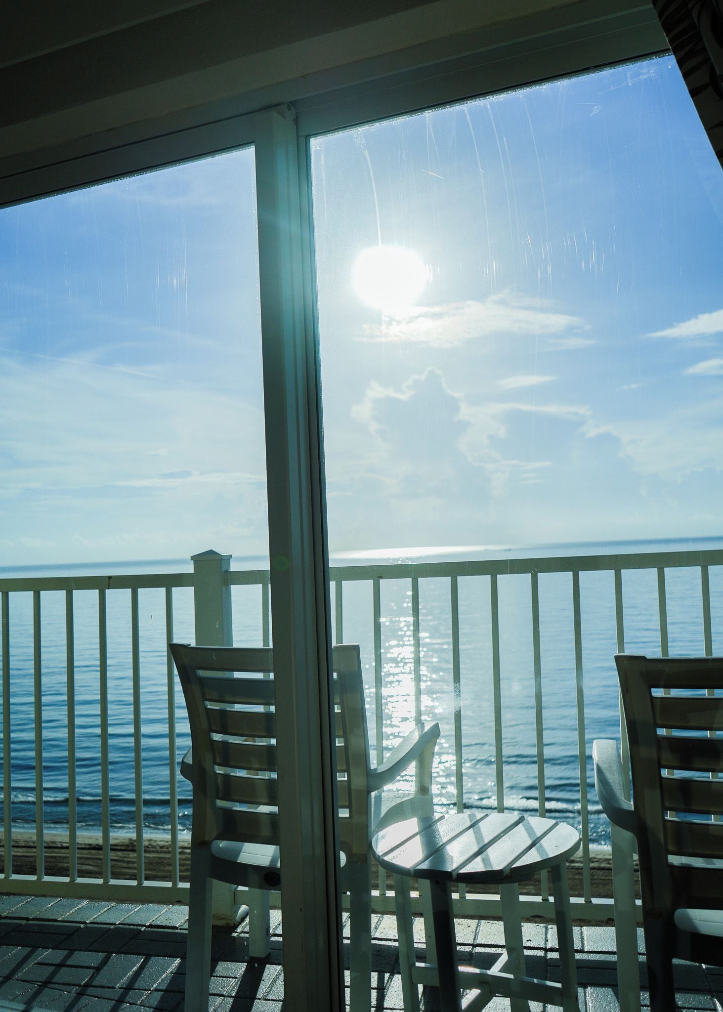 A balcony with a view of the ocean and a clear sky.
