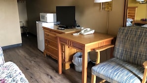 A hotel room with a wooden desk, a television, a telephone, a lamp, a chair, and a bed. - Knights Inn Baker City (Baker City)