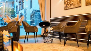 Een modern interieur met een zithoek, bestaande uit vier stoelen, een ronde tafel met een decoratie, en een groot raam met uitzicht op de stad.