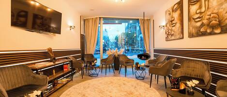 A modern living room with a large TV, comfortable seating, a round rug, and artwork on the walls.