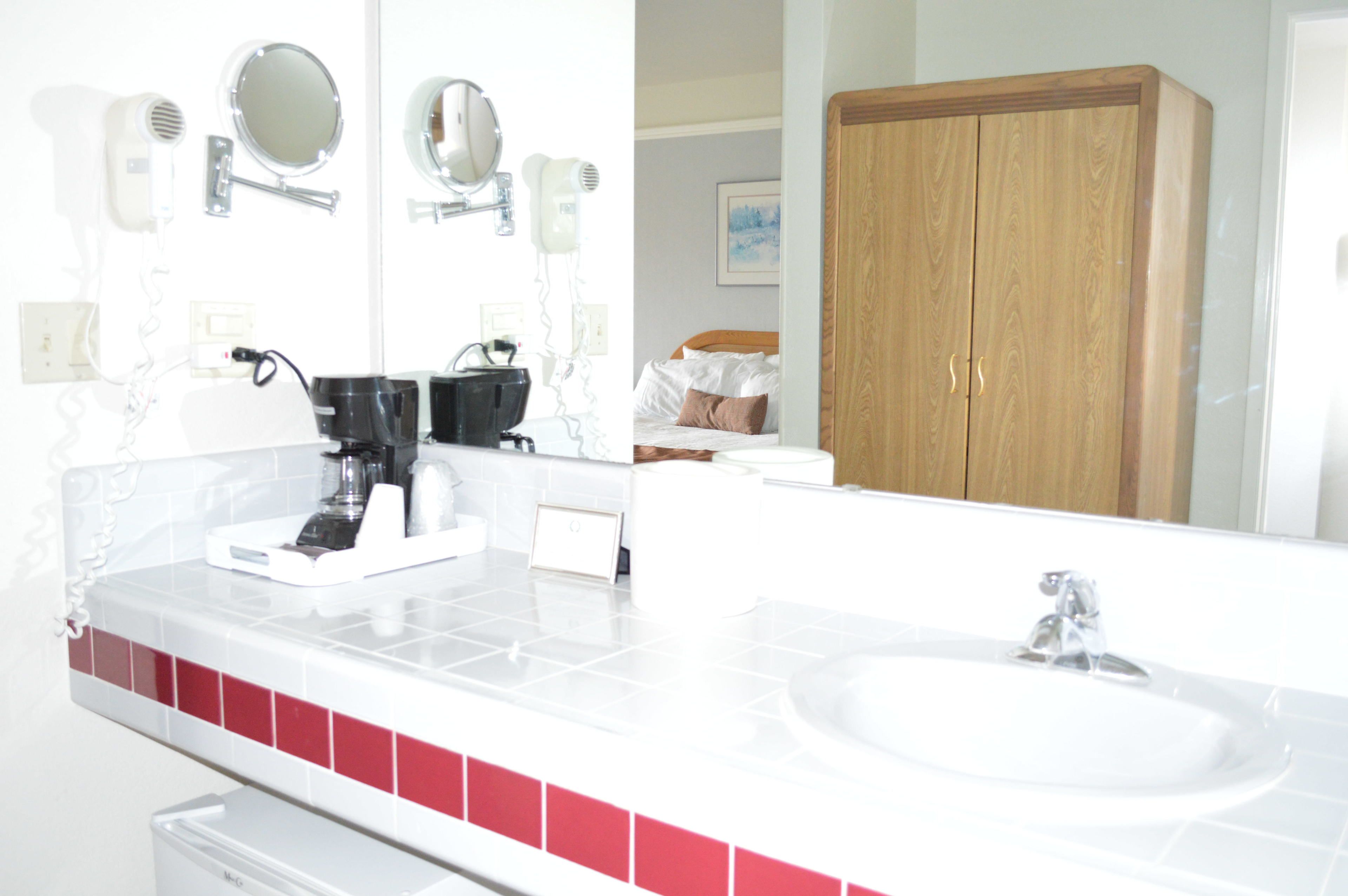 A bathroom with a white sink, a mirror, and a hairdryer.