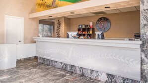 A reception desk with a clock, a bulletin board, and a painting above. - Laurel Inn Motel (Salinas)
