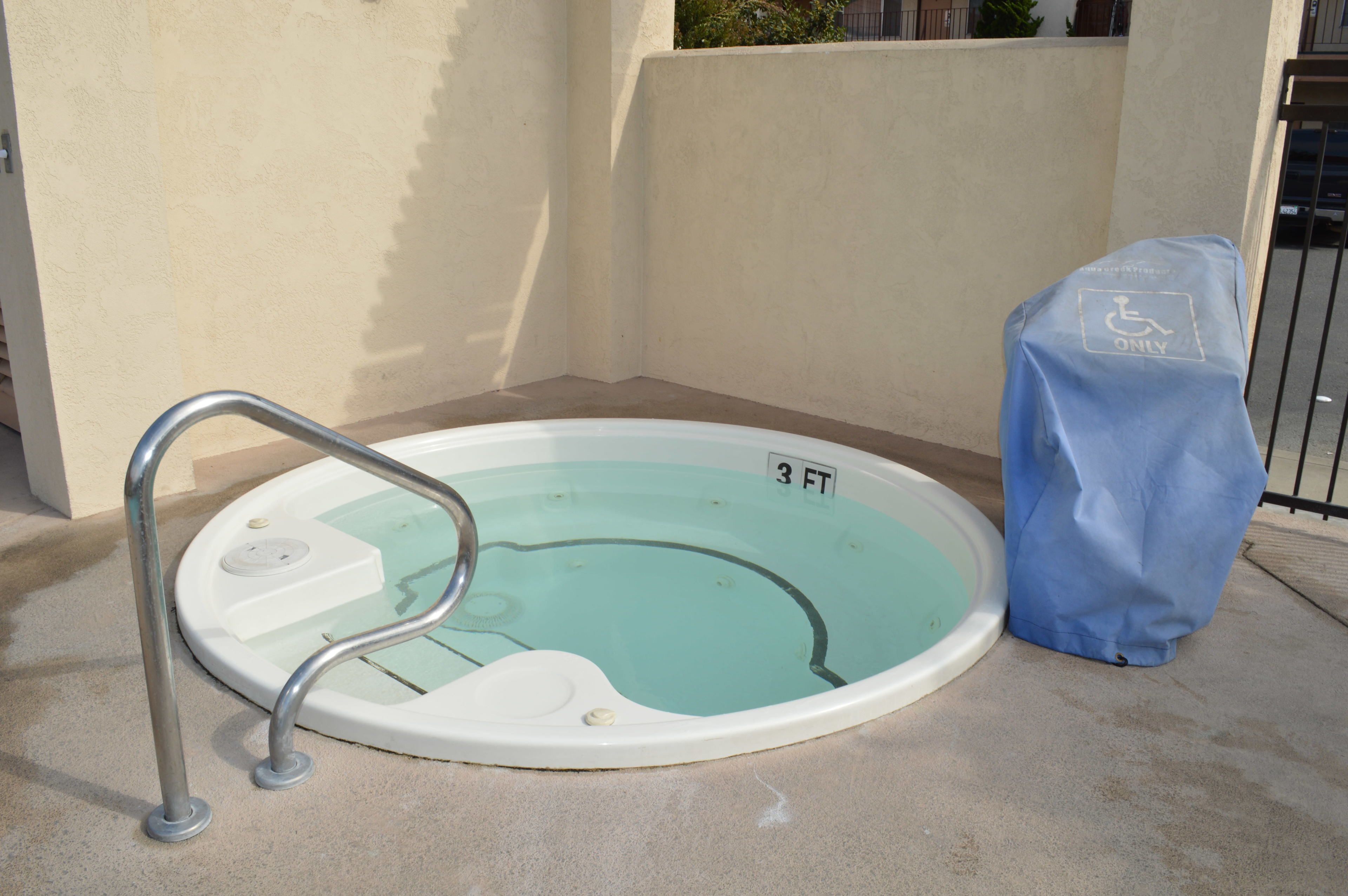 A small, round, indoor pool with a metal ladder and a cover marked "3 FT" and "ONLY" for accessibility.