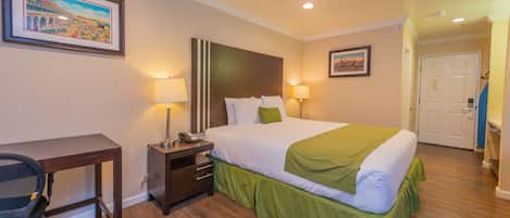 A hotel room with a bed, desk, chair, and two lamps.