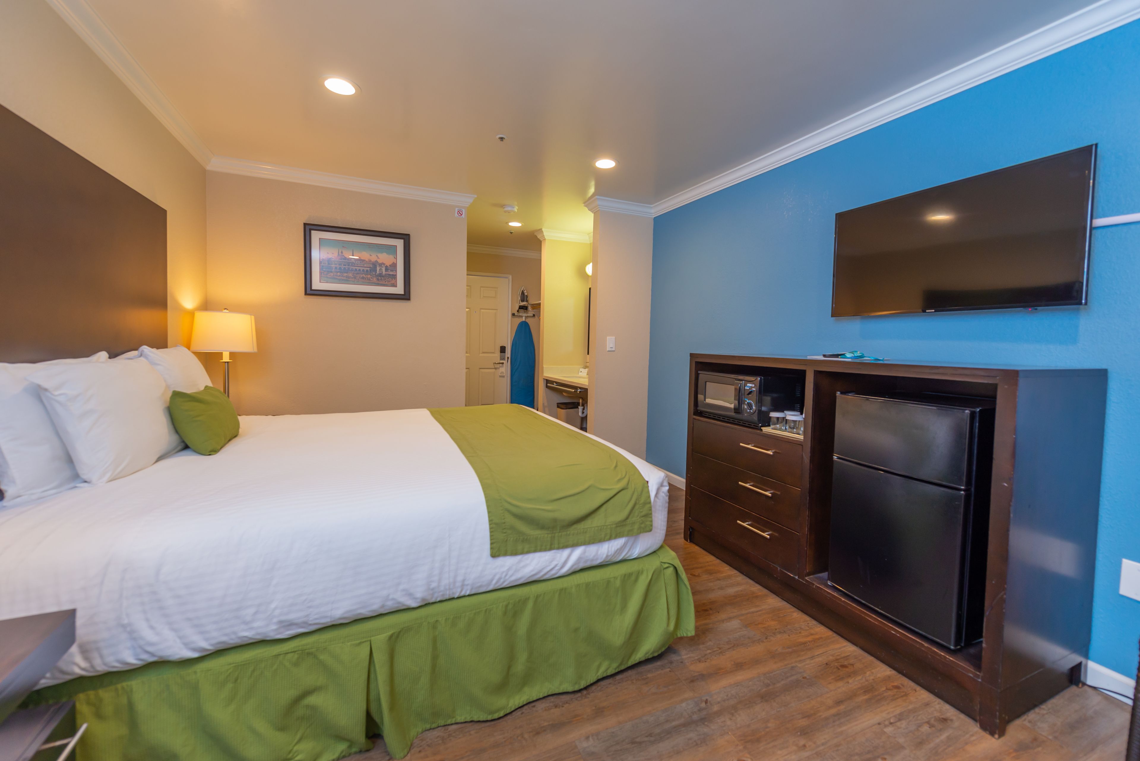Quarto de hotel com cama, televisão, escrivaninha e micro-ondas.