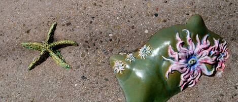 Una estrella de mar y una roca con flores pintadas sobre arena.