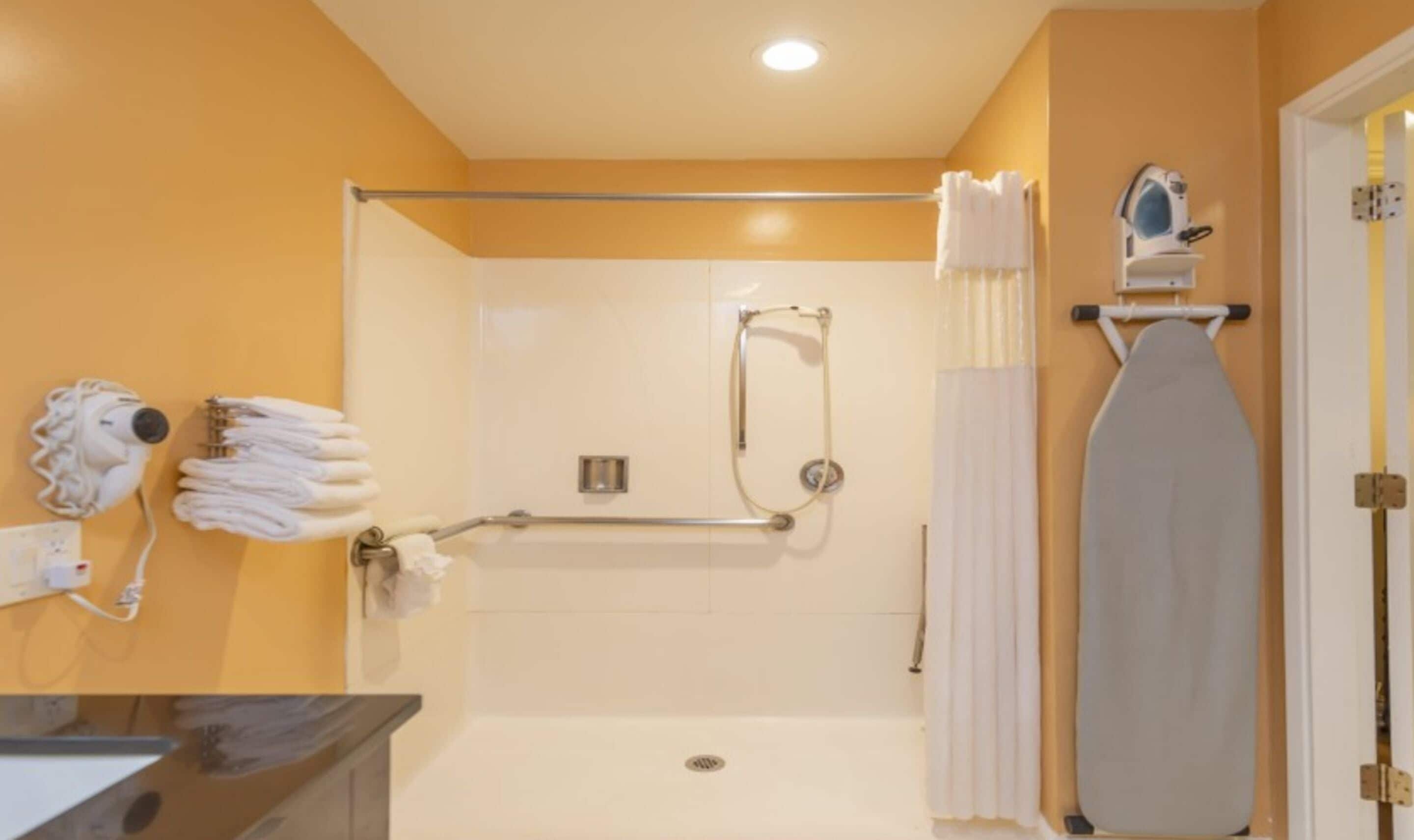 Un baño con ducha, toallero y secador de pelo.
