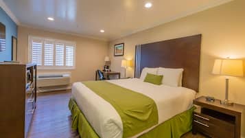 A hotel room with a large bed, bedside tables, a desk, and a chair.