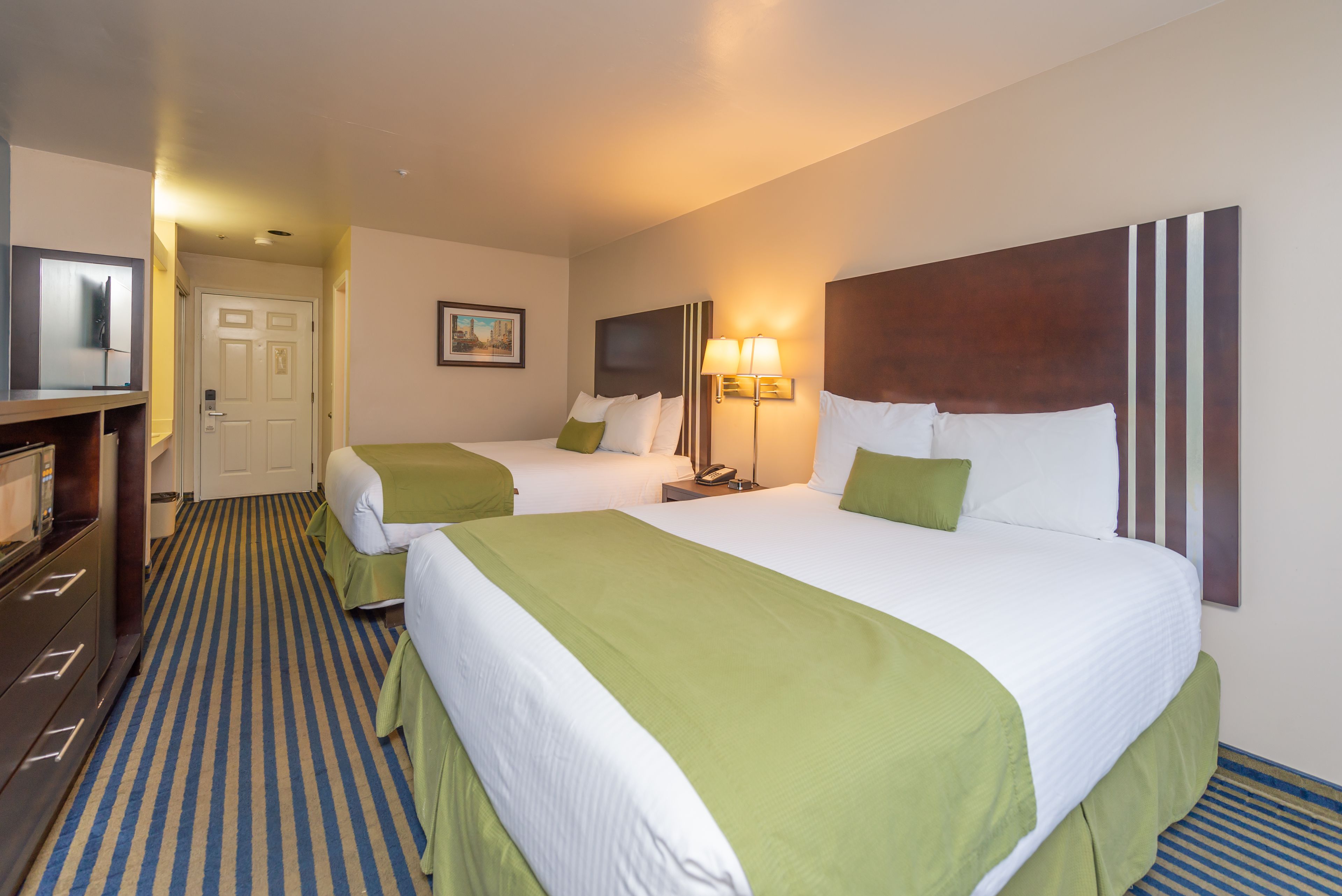 A hotel room with two beds, a television, a desk, and a lamp.