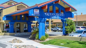 A building with a blue and yellow facade, a sign indicating no vacancies, and the name "Ocean Pacific Lodge". - Ocean Pacific Lodge (Santa Cruz)