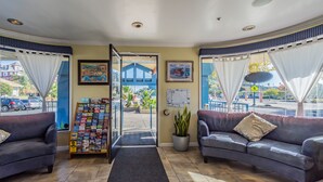 A reception area with two sofas, a plant, a map display, and a view of the outside. - Ocean Pacific Lodge (Santa Cruz)