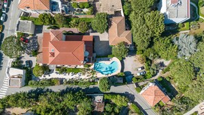 An aerial view of a residential area with multiple houses, a swimming pool, and a road. - Hôtel Beau Site - Cap d'Antibes (Antibes)