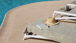 A poolside area with lounge chairs, a sun umbrella, and a straw hat. - Hôtel Beau Site - Cap d'Antibes (Antibes)