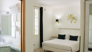 A bedroom with a bed, bedside table, and a wall-mounted lamp. - Hôtel Beau Site - Cap d'Antibes (Antibes)