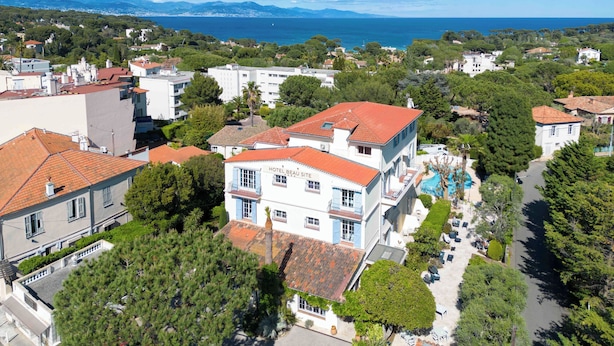 A hotel with a red-tiled roof, a swimming pool, and a view of the sea. - Hôtel Beau Site - Cap d'Antibes (Antibes)