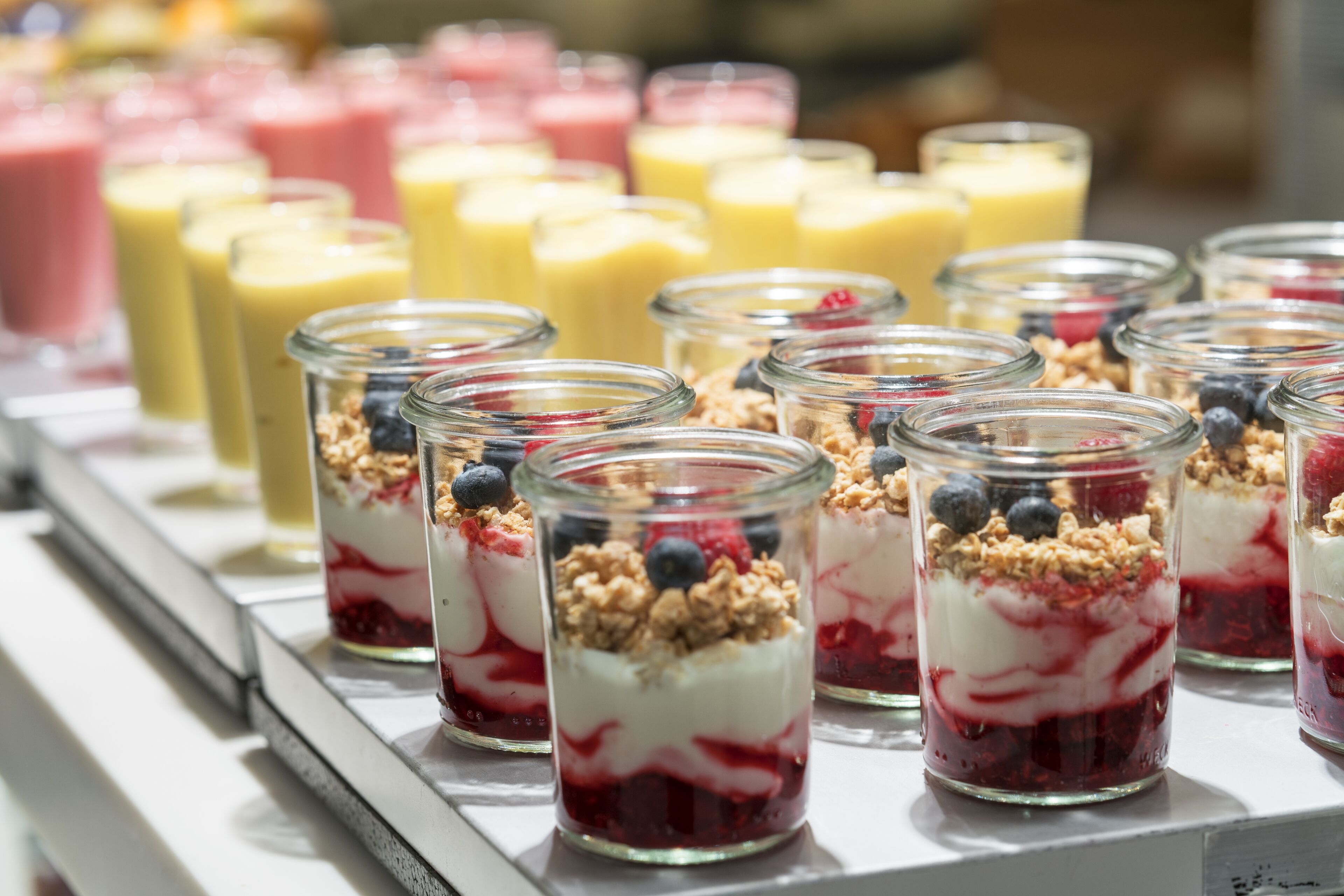 A variety of colorful parfaits in glass jars, arranged on a tray.