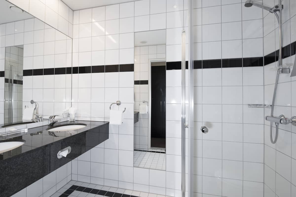 A modern bathroom with two sinks, a large mirror, and a shower area.