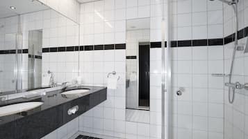 A modern bathroom with two sinks, a large mirror, and a shower area.