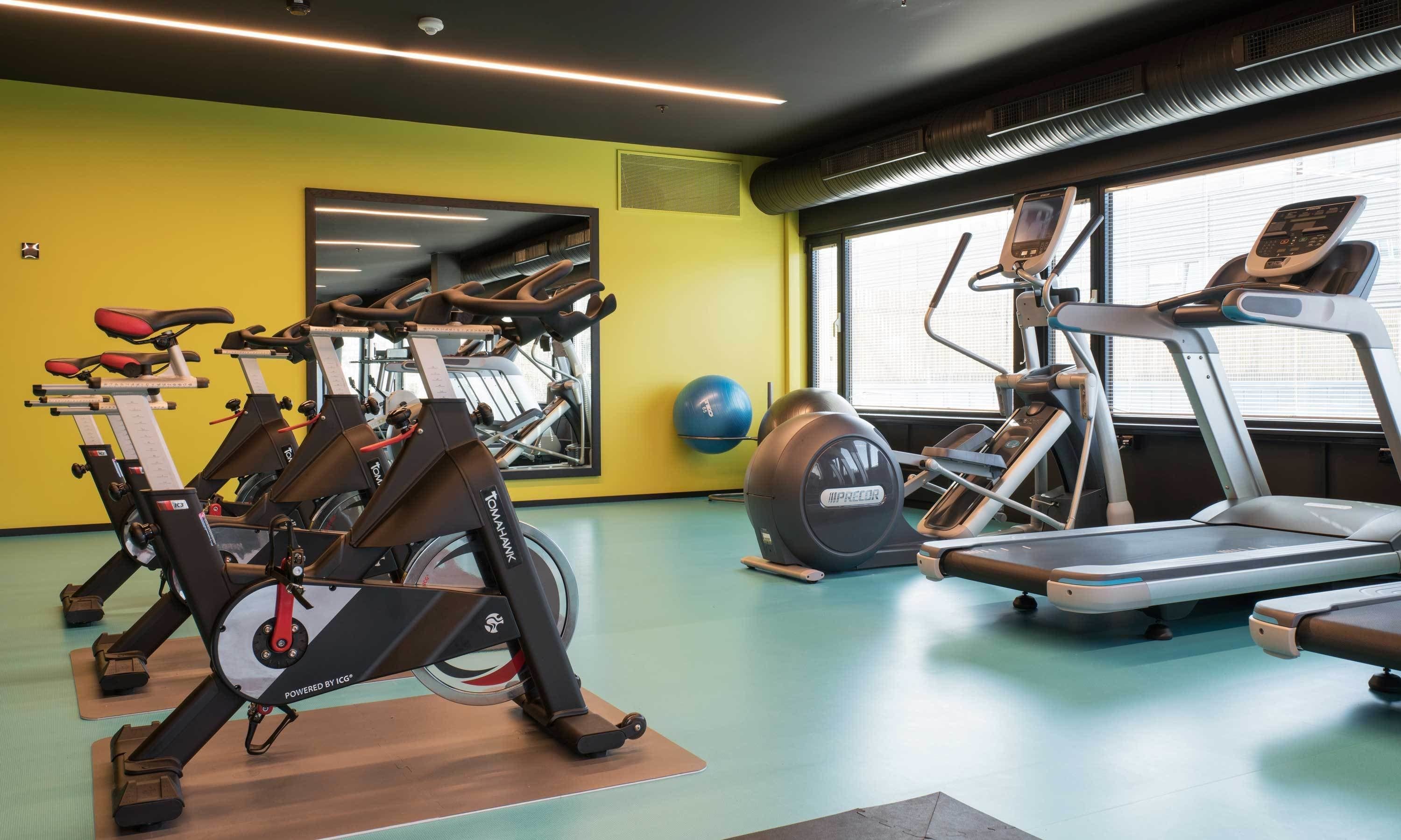 Une salle de sport équipée de vélos d’appartement, de tapis de course et de ballons d’exercice.