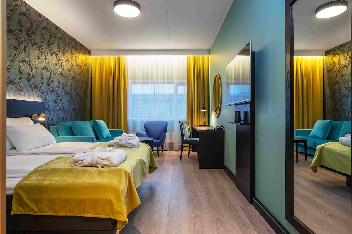 A hotel room with two beds, a desk, a chair, and a mirror.