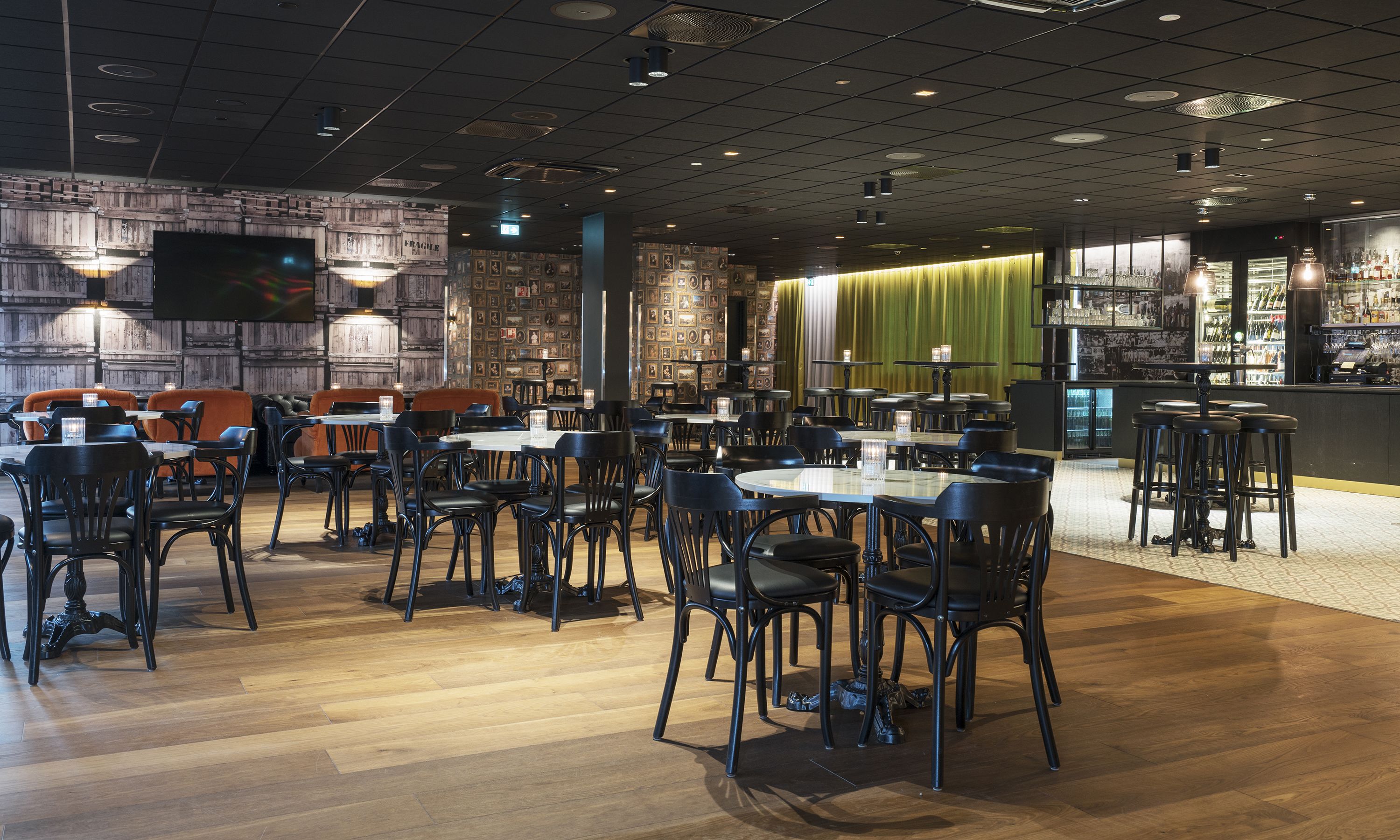 A restaurant with wooden walls, black chairs, and a bar area.