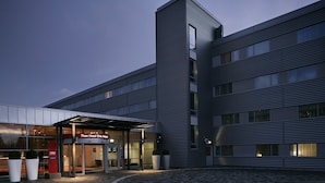 Un hôtel moderne doté d’une tour d’angle imposante, de grandes fenêtres et d’une entrée en verre.