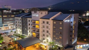 Un hotel Courtyard con varios pisos, un estacionamiento y un área exterior cubierta con palmeras.