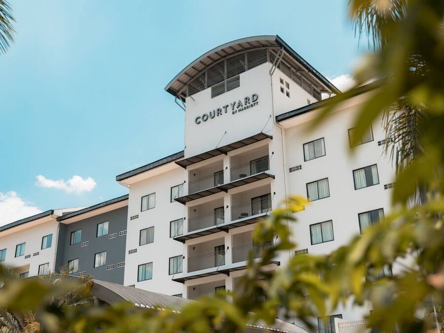 A multi-story hotel with a prominent 'Courtyard by Marriott' sign, balconies, and a modern architectural design.