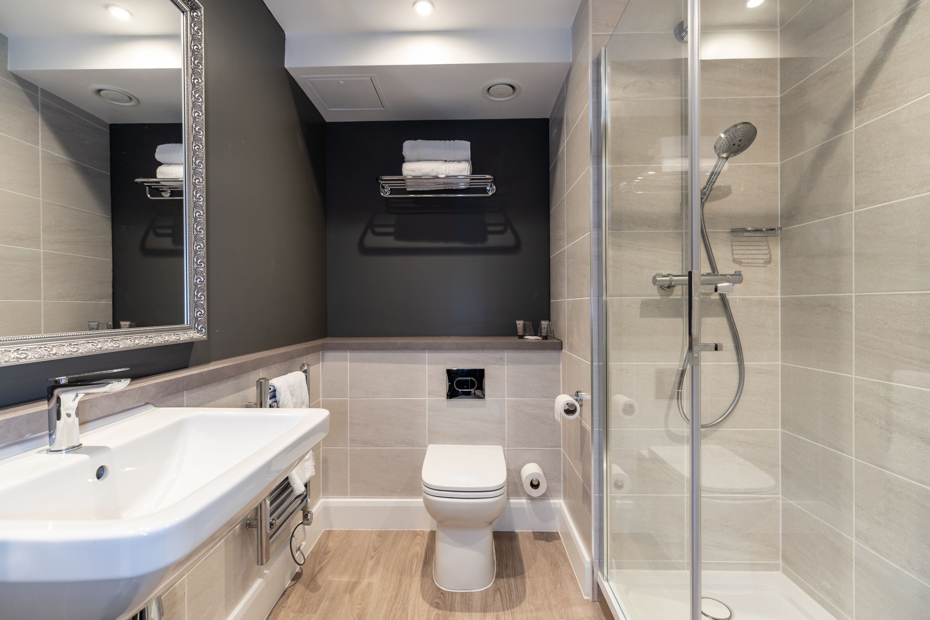 A modern bathroom with a glass-enclosed shower, a white sink, and a toilet.