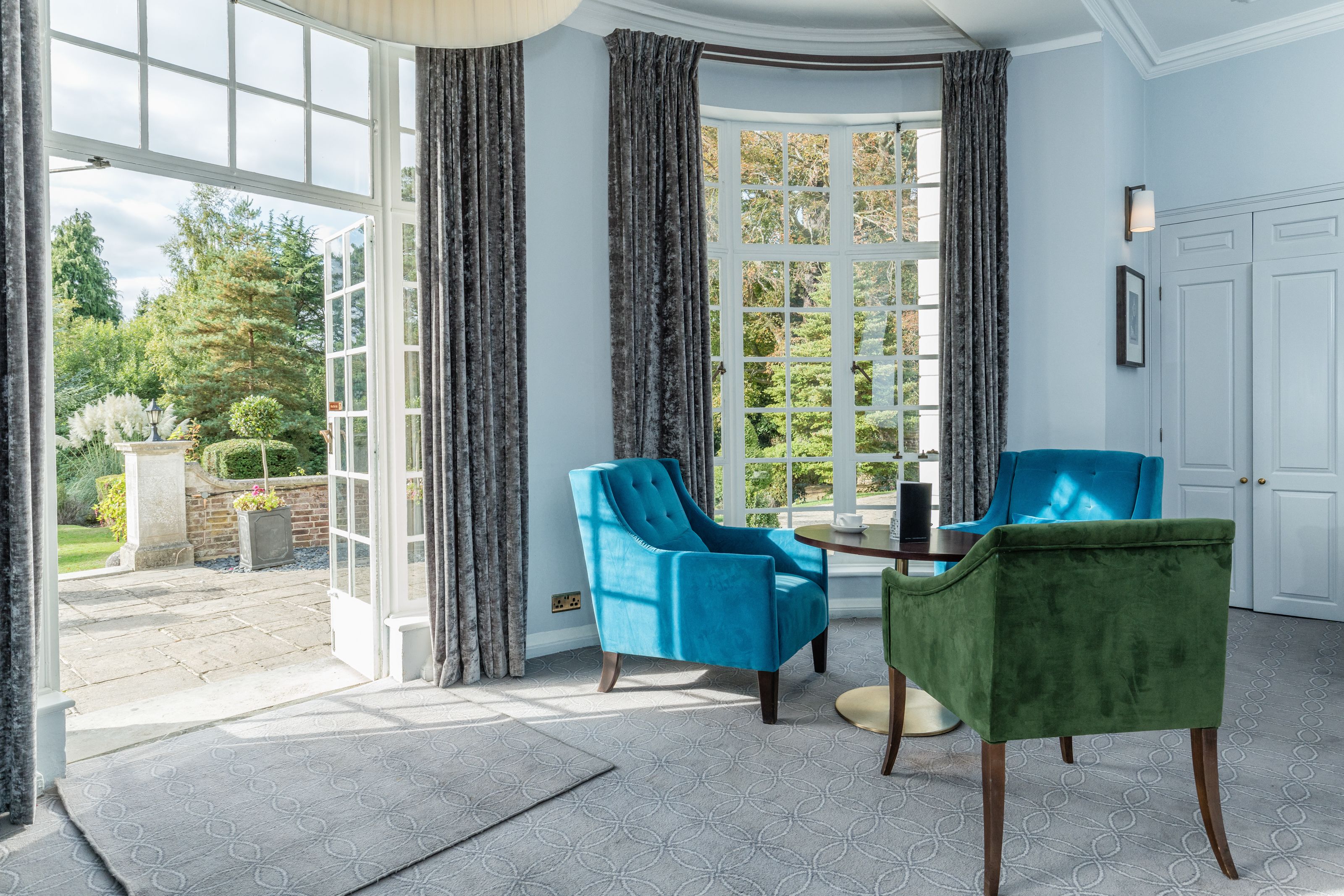 A room with a large bay window, two chairs, a table, and a door.
