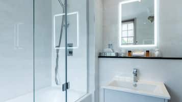 A modern bathroom with a glass-enclosed shower, a white sink, and a vanity with a mirror.
