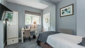 Un dormitorio con cama, escritorio, silla, radiador y ventana con persianas.