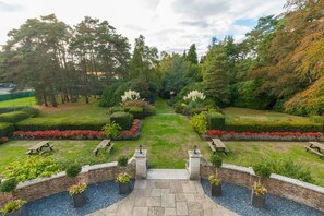 A well-maintained garden with a central pathway, benches, and a brick wall. - Gorse Hill (Woking)