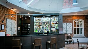 En bar med murstensvæg, et glasmontre med flasker og tre træbarstole.