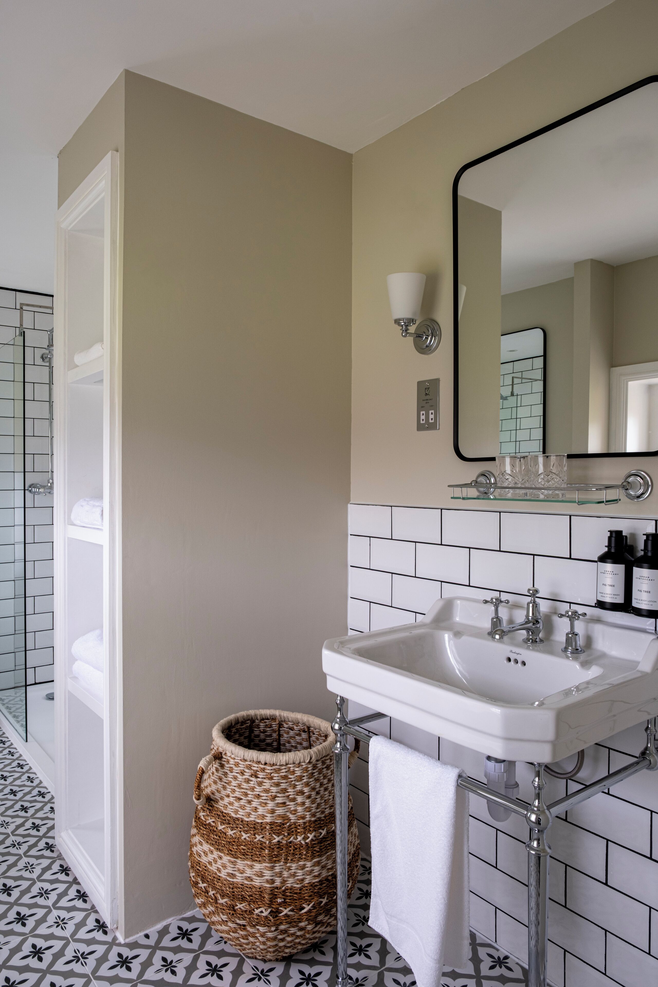A bathroom with a white sink, a mirror, and a glass shelf above it.