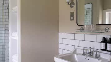 A bathroom with a white sink, a mirror, and a glass shelf above it.