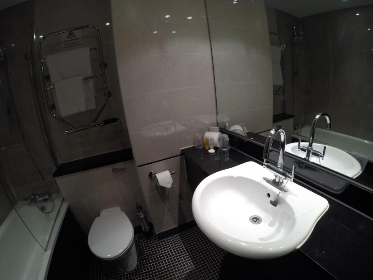 Een moderne badkamer met een wit wastafel, een spiegel en een toilet.