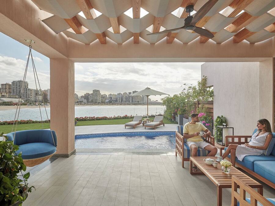 Uma área de estar moderna ao ar livre, com piscina, cadeira de balanço suspensa e vista para o horizonte da cidade.