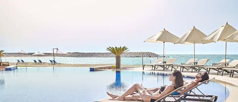 Una piscina cubierta, una piscina al aire libre de temporada, sombrillas