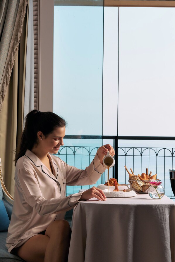 A person sitting at a table with a cup, a basket of bread, and a vase with flowers.