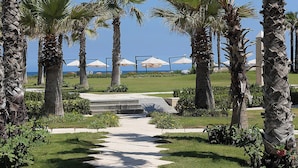 A pathway lined with palm trees leading to beach umbrellas. - Four Seasons Hotel Alexandria at San Stefano (Alexandria)