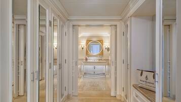 Een gang die leidt naar een badkamer met een wastafel, een grote spiegel en een bord met daarop Four Seasons Hotel.