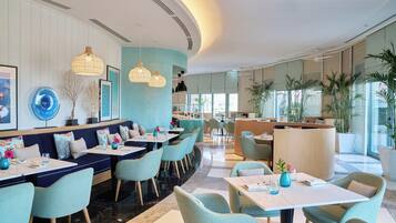 Un ristorante moderno con un'area salotto curvo, una reception e ampie finestre che lasciano entrare la luce naturale.
