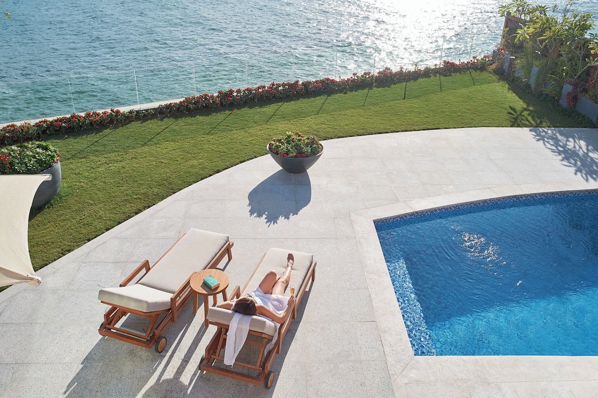 A poolside area with lounge chairs and a person relaxing by the pool.
