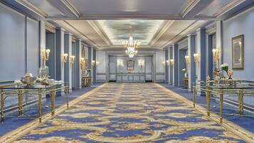 Um hall imponente com carpete azul, detalhes dourados e lustres.