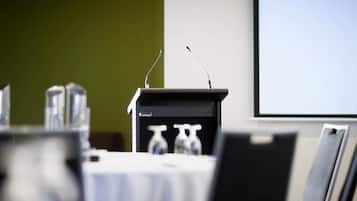 A conference room with a podium, chairs, and a projector screen.