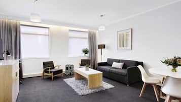 A modern living room with a sofa, coffee table, and a dining table with chairs.